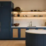 Matte navy blue kitchen cabinetry with brushed brass hardware, rattan inset doors and open oak shelving in an Italian transitional Australian kitchen