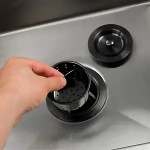 用手将黑色篮式滤网从厨房水槽的不锈钢排水口中取出