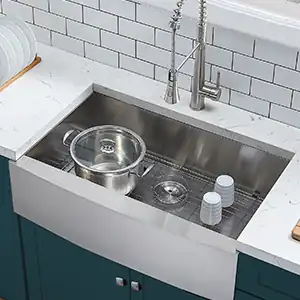 在铺有白色地铁砖的青绿色厨房中，摆放着带锅和杯子的拉丝不锈钢农舍式围裙式水槽