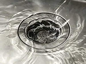 特写镜头:水流经带滤篮的不锈钢水槽排水口