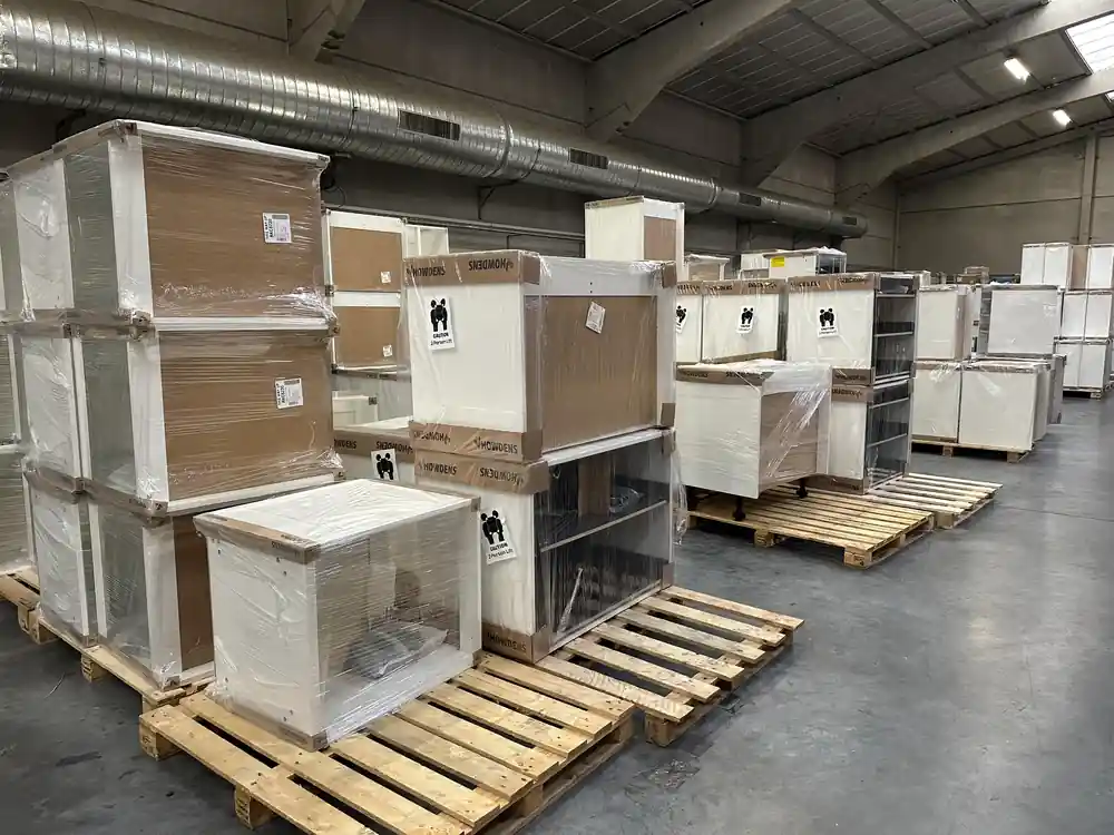 Stacked packaged bathroom vanities on wooden pallets inside a large warehouse
